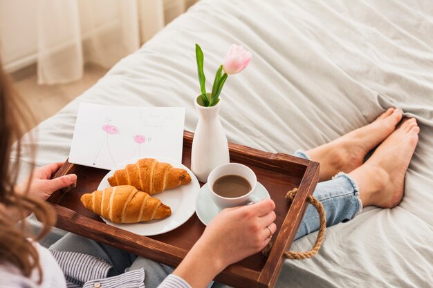 Vrouwenzitting op bed met koffie op dienblad