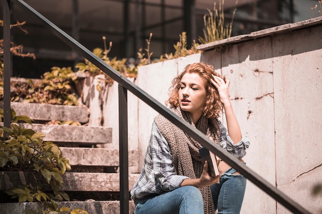 Gratis foto vrouwenzitting op stappen en het aanpassen van haren