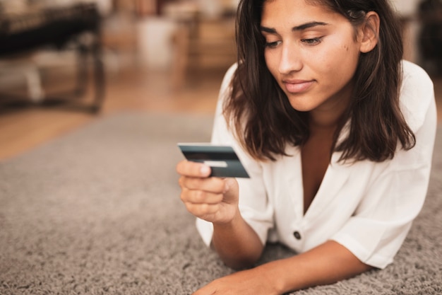 Vrouwenzitting op vloer en het bekijken een creditcard