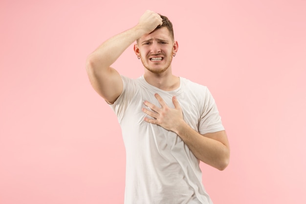 Waarom is dat. Mooie mannelijke halve lengte portret geïsoleerd op trendy roze studio achtergrondgeluid. Jonge emotioneel verraste, gefrustreerde en verbijsterde man. Menselijke emoties, gezichtsuitdrukking concept.