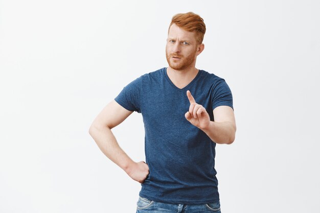 Wacht even, ik verbied je. Strikte, ernstig uitziende jonge vader met rood haar en baard, met wijsvinger zwaaien en ontevreden staren, nee zeggen of niet, hand op taille vasthouden, kind uitschelden