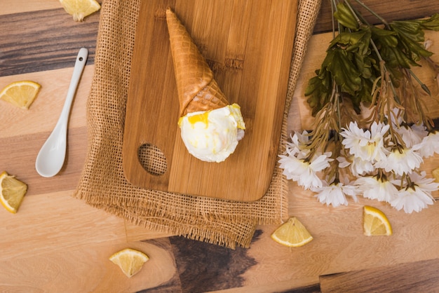 Wafelkegel met ijs aan boord in de buurt van plakjes vers fruit en bloemen