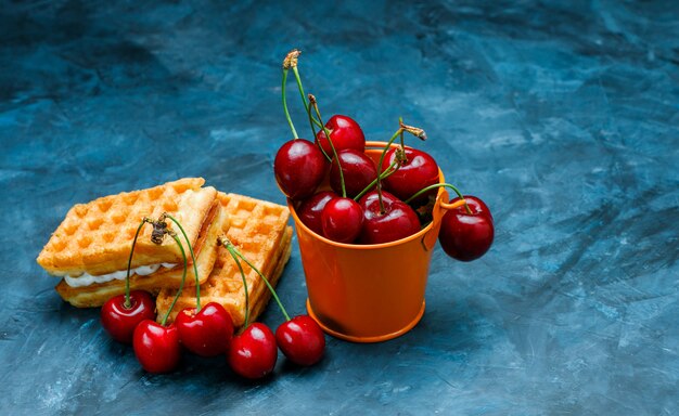 Wafels met kersen op grungy blauwe oppervlakte, hoge hoekmening.