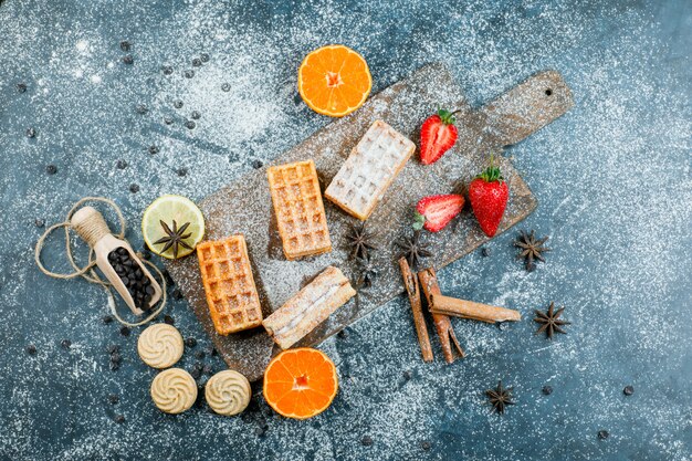 Wafels met specerijen, koekjes, choco chips, fruit bovenaanzicht op grungy en snijplank oppervlak