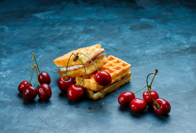 Wafels met uitzicht op de hoge hoek van kersen op een grungy blauwe oppervlak