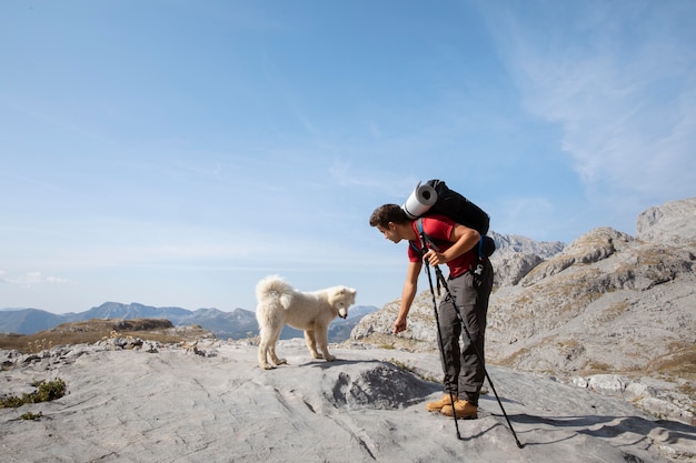 Wandelaar die een schattige witte hond op de bergen sticht