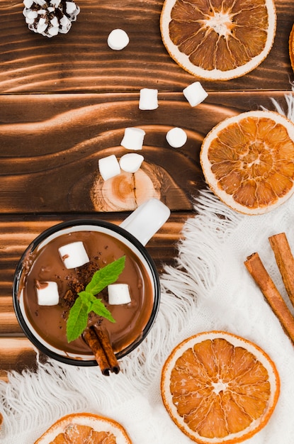 Warme chocola op het bureau met wollen laken, marshmallows en citroenen