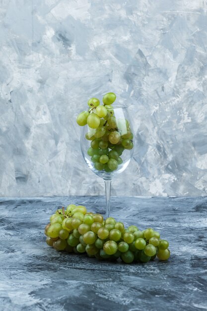 Wat glas witte druiven op donkere en lichtblauwe marmeren achtergrond, close-up.