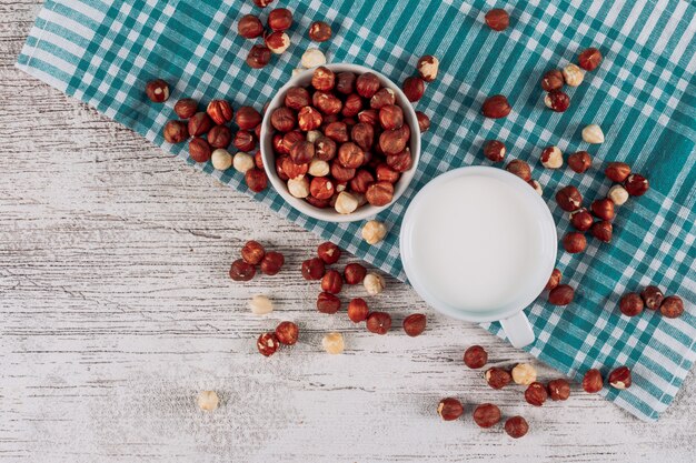 Wat kop melk met kom van hazelnoten op witte houten en blauwe doekachtergrond, hoogste mening.