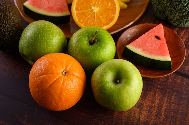 Watermeloen, sinaasappelen, in stukjes gesneden met avocado en appels op houten tafel.