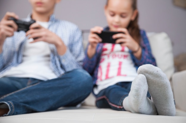 Wazig broers en zussen spelen van videogame en het gebruik van smartphone