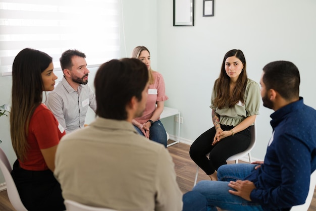 We zijn hier voor jou. Diverse mensen op een alcoholische anonieme bijeenkomst luisteren naar de ervaring met verslaving van een nieuw lid van de groep