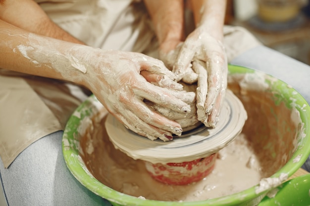 Wederzijds creatief werk. handen die een kom op een aardewerkschijf creëren in een kleistudio.