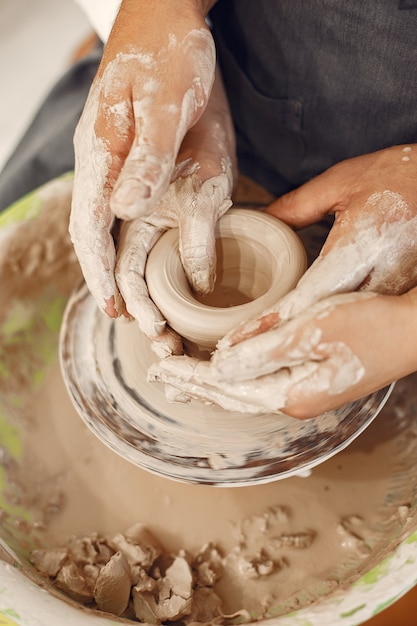 Wederzijds creatief werk. jong mooi paar in vrijetijdskleding en schorten. mensen maken een kom op een aardewerkschijf in een kleistudio.