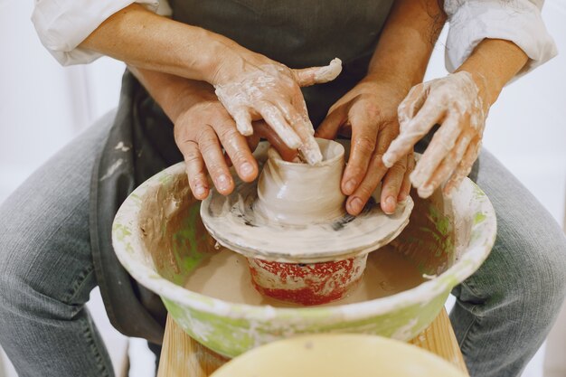 Wederzijds creatief werk. Volwassen elegant paar in vrijetijdskleding en schorten. Mensen maken een kom op een aardewerkschijf in een kleistudio.