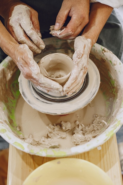 Wederzijds creatief werk. Volwassen elegant paar in vrijetijdskleding en schorten. Mensen maken een kom op een aardewerkschijf in een kleistudio.