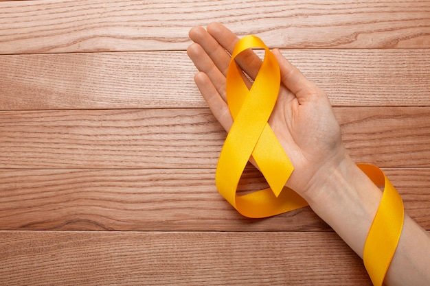 Gratis foto weergave van geel lint met menselijke hand op houten achtergrond