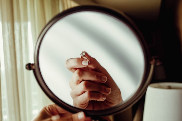 Weerspiegeling van de hand van de woma met verlovingsring in een spiegel