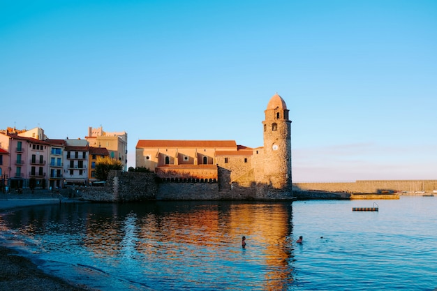 Weerspiegeling van een oud kasteel in het kalme water van de zee onder de blauwe hemel