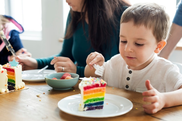 Weinig jongen die een regenboog gekleurde cake eet