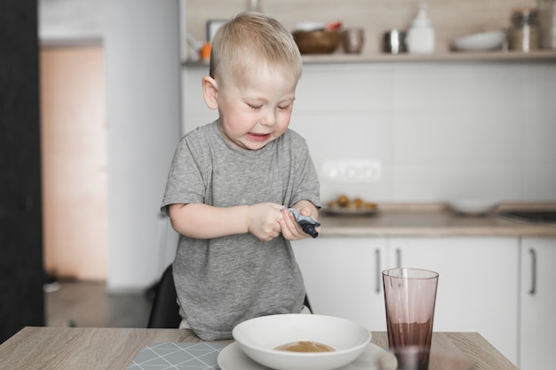 Weinig jongen die zich op stoel bevindt die het pakket in de kom drukt