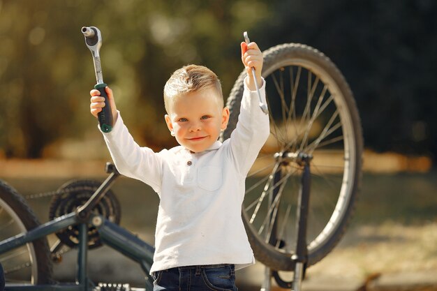 Weinig jongen herstelt zijn fiets in een park
