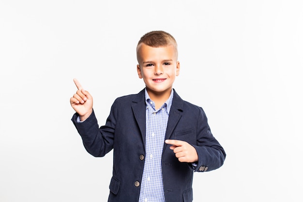 Weinig jongen met het lege richten hief hand op, op witte muur wordt geïsoleerd die