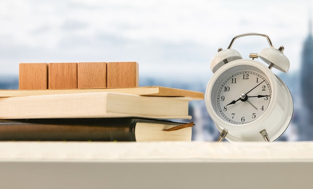 Wekker en houten kubussen op boeken op een tafel