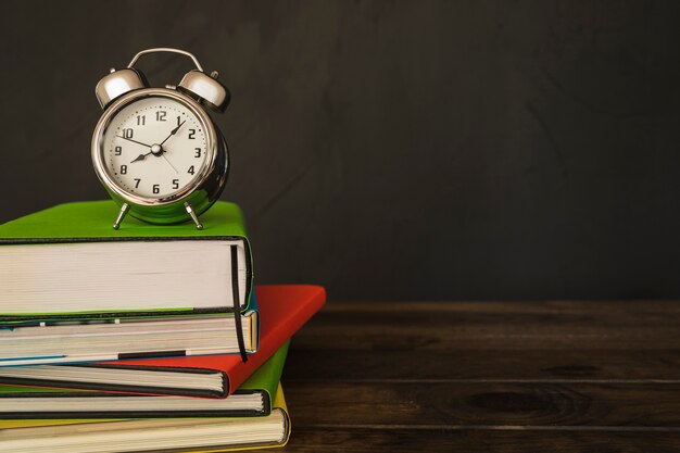 Wekker met boekenstapel op bureau