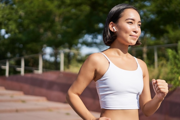 Welzijn en sport Aziatische fitness meisje runner joggen in park rennen op straat in legging glimlachend