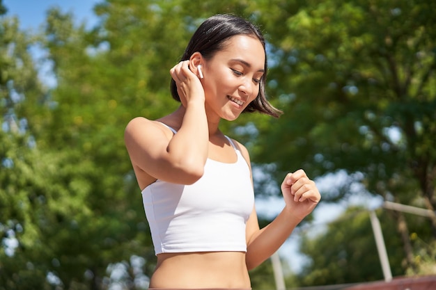 Welzijn glimlachend aziatische fitness meisje runner in park glimlachend en rennend joggen workout outdoo