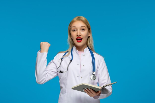 Wereldartsendag schattige dokter met vuist en notitieboekje met de stethoscoop in de laboratoriumjas