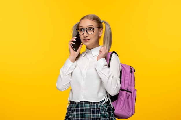 Wereldboekendag blond schoolmeisje praten op de mobiele telefoon op gele achtergrond