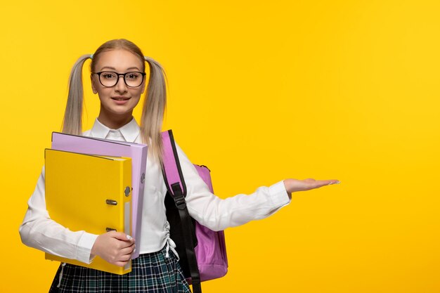 Wereldboekendag lachend schoolmeisje in uniform op gele achtergrond met rugzak