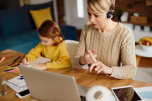 Werkende moeder met telefonische vergadering via laptop thuis