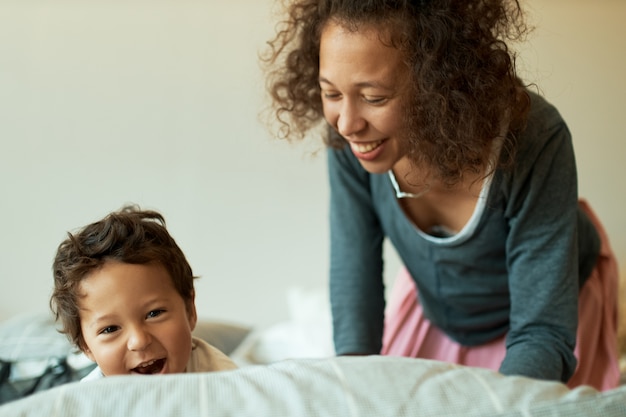 Werkloze jonge vrouw met krullend haar lachen met plezier met haar zoon