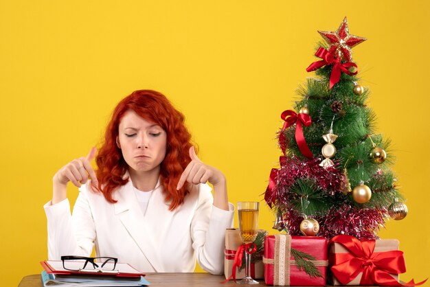 werkneemster zittend achter tafel met cadeautjes en bestanden op geel