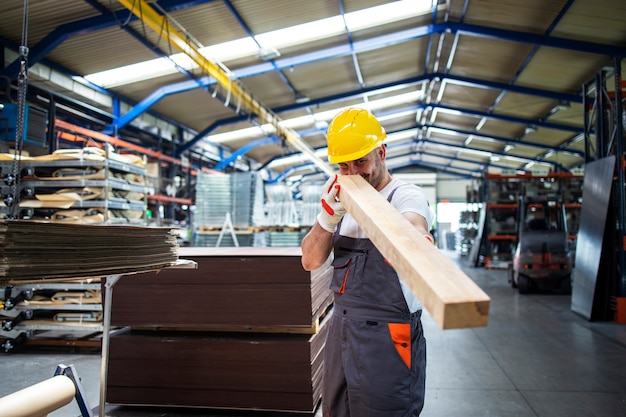 Werknemer die houten plank houdt en in meubelfabriek of houtverwerkende industrie werkt