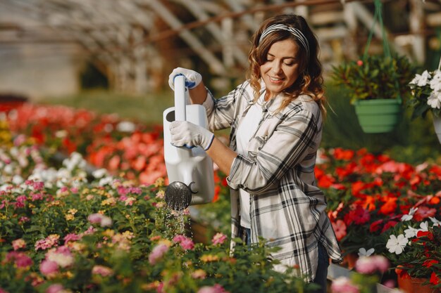 Werknemer giet flowerpoots. Meisje in een wit overhemd. Vrouw met trechter