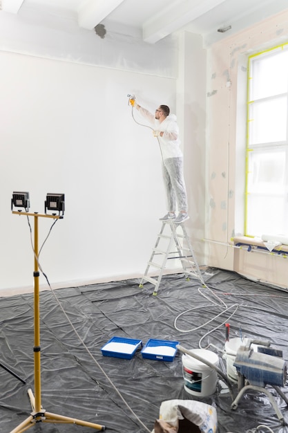 Werknemer schilderij muur op ladder volledig schot