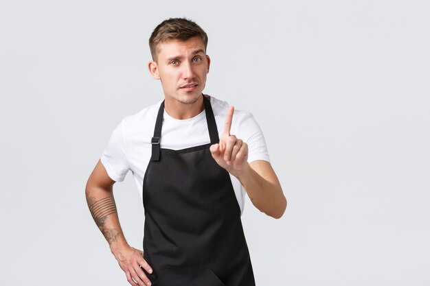 Werknemers, supermarkten en coffeeshopconcept. Serieus ogende knappe barista die les geeft over hoe je koffie thuis zet, vinger schudt als uitbrander, iets verbiedt of verbiedt