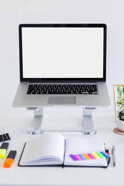 Werkplek met laptop op staan in de buurt van notebook, markeringen en stickers