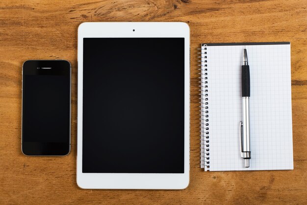 Werkplek. Telefoon, tablet en notitieblok op tafel