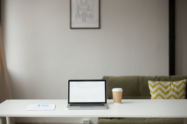 Werktafel met laptop, koffie en documenten in interieur