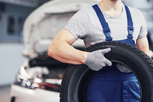 Werktuigkundige die een bandband houdt bij de reparatiegarage. vervanging van winter- en zomerbanden