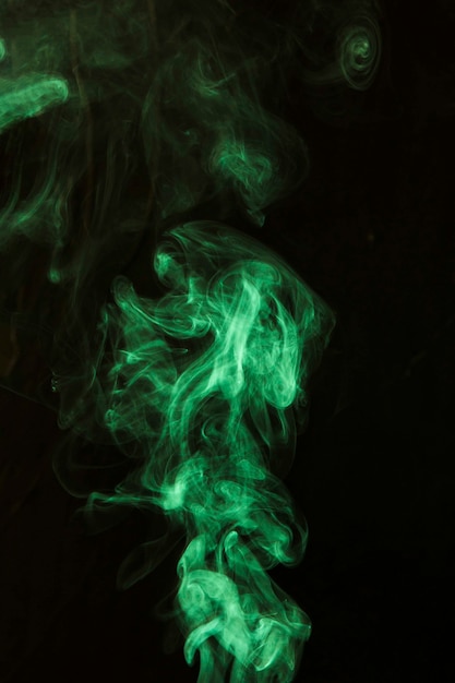 Werveling van groene rook tegen zwarte donkere achtergrond