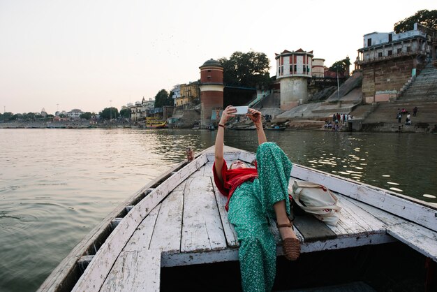 Westerse vrouw liggend op een boot met selfies in Varanasi