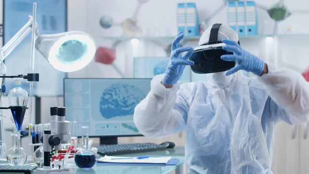 Wetenschapper-onderzoeker-arts die virtual reality-googles draagt en hersenactiviteitsstructuur analyseert en gebaren maakt met handen tijdens biochemisch experiment in microbiologisch laboratorium. geneeskunde concept