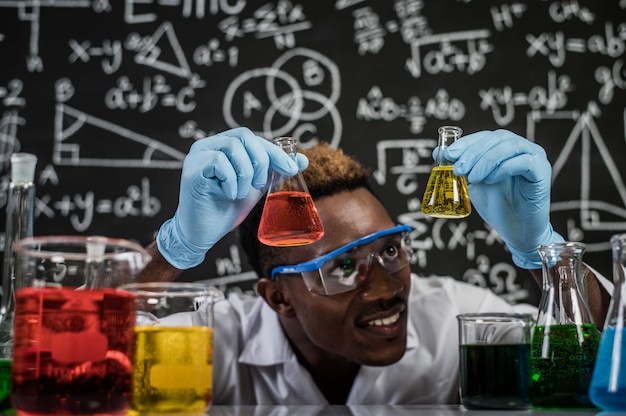 Gratis foto wetenschappers kijken naar de gele chemicaliën in glas in het laboratorium