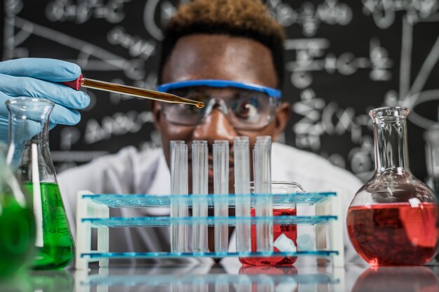 Wetenschappers laten in het laboratorium oranje chemicaliën in het glas vallen